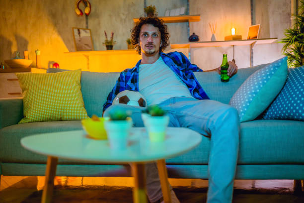 istock Man watching football game at home 1331523183