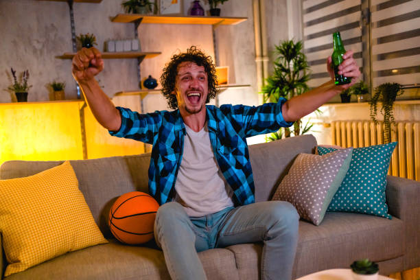 istock Man cheering while watching basketball on TV 1331525030