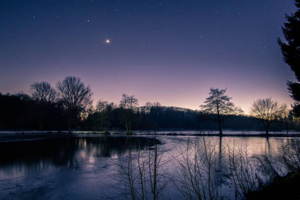crépuscule le soir d’hiver avec des étoiles et vénus sur le ciel nocturne au paysage du lac avec des silhouettes d’arbres et de réflexion - lake night winter sky photos et images de collection
