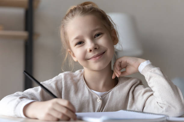 portrait en chef souriante fille d’âge primaire élève au bureau - looking at camera smiling desk isolated photos et images de collection