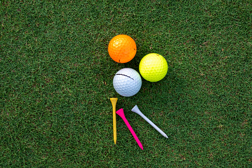 Golf glove ,colorful ball ,tee and gold club put on green grass of golf course ,This objects for play
