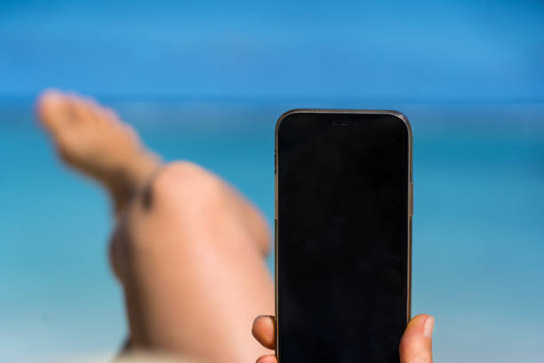 Happy traveler woman enjoys at tropical beach while using smart phone on vacation, Cook Islands, Rarotonga. Summer on beach concept.