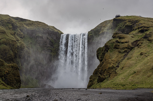 Majestic Skogafoss Waterfall under moody overcast cloudscape in summer. Falling water of the Skoga River. The Skógafoss is one of the biggest waterfalls in Iceland, with a width of 25m and a drop of 60m. Skógar, Rangárþing eystra, Southern Iceland, Sudurland, Iceland, Nordic Countries, Europe