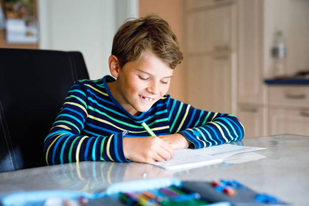 istock Hard-working happy school kid boy making homework during quarantine time from corona pandemic disease. Healthy child writing with pen, staying at home. Homeschooling concept 1331565793