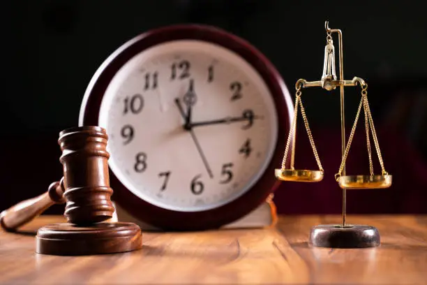 Photo of Concept showing of Problems with legal system, delay or slow in judicial justice system by using judge hammer, balance scale and wall clock.