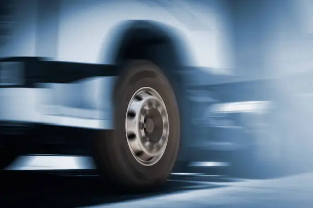 Front of Semi Truck Wheels Spininng, Speed Motion Blur Driving on The Road. Industry Road Freight by Truck. Logistic and CargoTransport concept.
