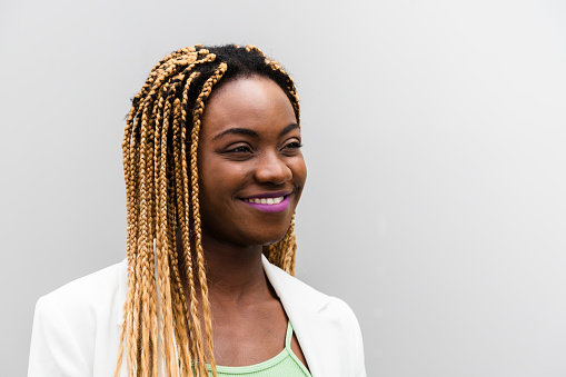 Portrait of smiling young african american woman with long blond braids. Copyspace.