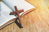 istock Closeup of simple wooden Christian cross necklace on Old Bible. Christian background with copy space 1331574354