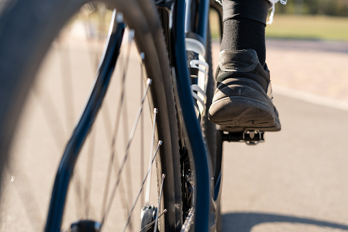 Cropped shot of man in sneakers riding a bicycle, feet on pedals. Copy space.