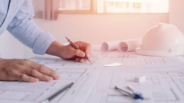 istock Young engineers holding a black pen pointing to a building on a blueprint. selective focus, Business construction concept. 1331579511