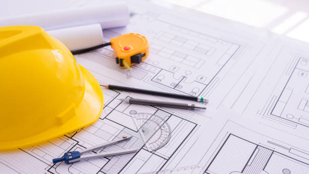 istock Yellow helmet and heap of drawing a project on a work desk. Project papers and tools beside. Free space in the middle. Flat lay, Construction background. Engineering tools. Copy space 1331581029