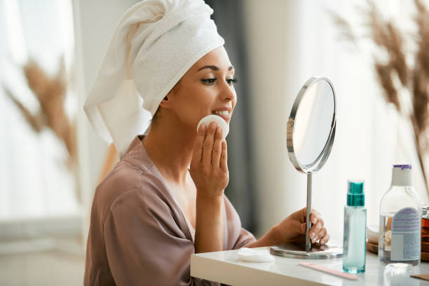 istock Young woman removing make-up of her face while looking herself in a mirror 1331592632