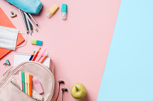 Creative student desk with colorful modern school supplies on blue and pink duotone background. Top view. Flat lay. Copy space. Back to school concept