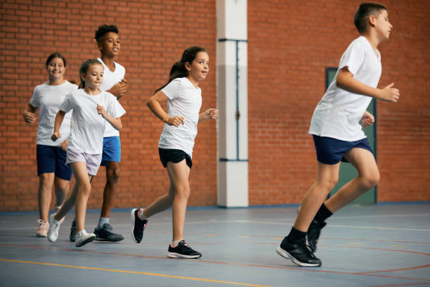 istock Full length of elementary students running while having PE class at school gym. 1331595023
