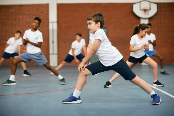 istock Elementary student and his friends warming up during PE class at school gym. 1331595144