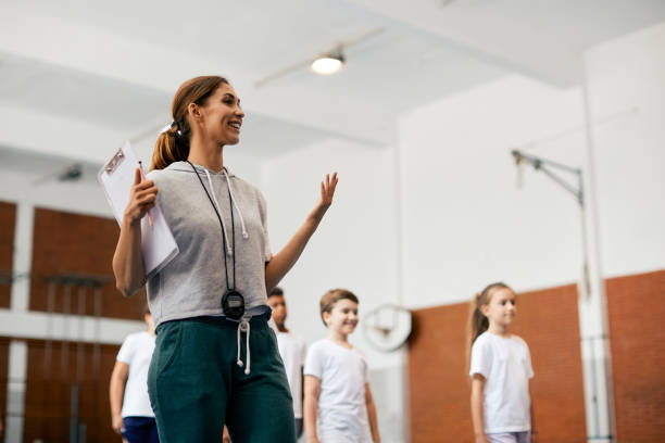 istock Happy female coach having a class with elementary students at school gym. 1331595157