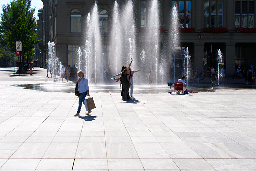 Children playing with jets of water of fountain at Federal Square at City of Bern on a beautiful summer day. Photo taken July 29th, 2021, Zurich, Switzerland.