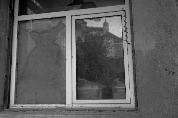 istock Old broken window in black and white color. One window pane is replaced with cardboard. 1331598559
