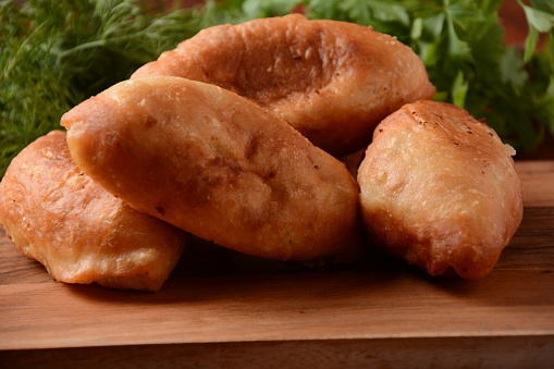 Russian Patties (Pasties, Hot Cakes, Pirozhki, Pies) on wooden cupboard . Traditional homemade fried pies  with potatoes