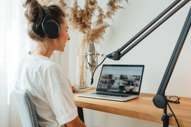 istock Female podcaster recording her podcast using microphone and laptop at his small home broadcast studio. Woman streaming live from homemade radio studio 1331601778