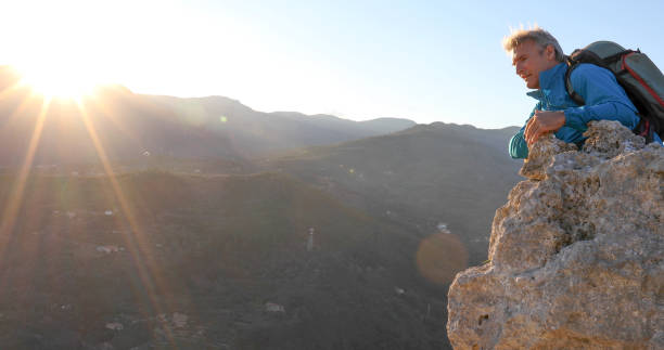 istock Mature man relaxes on mountain summit at sunset 1331603887