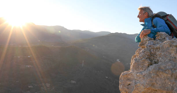 istock Mature man relaxes on mountain summit at sunset 1331603895