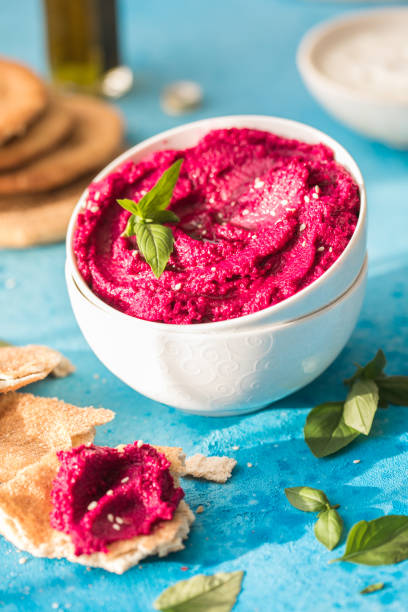 istock Hummus Bowl. Red beetroot hummus with fresh vegetables, olive oil on table 1331604537