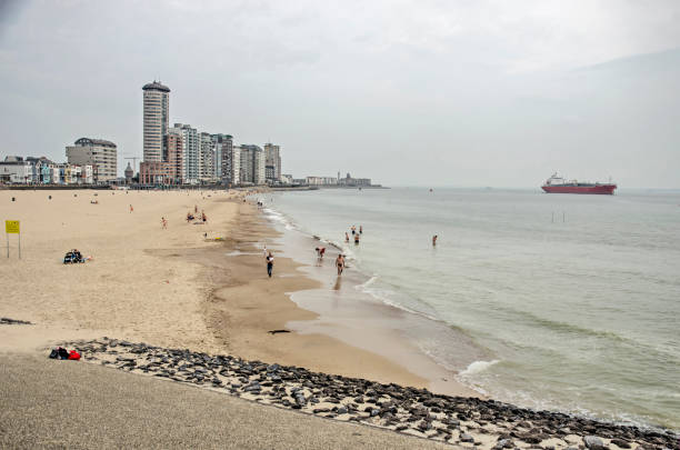 Vlissingen, The Netherlands, July 24, 2021: part of the city's seafront with a sandy beach, a modern skyline and a seagoing vessel