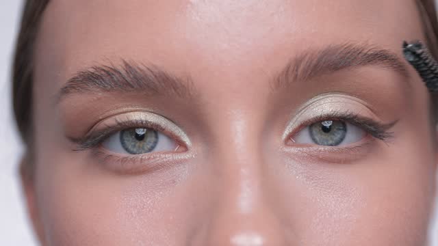 The make-up artist combs the eyebrows and makes the styling of the eyebrows with a gel.