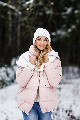 portrait of a young beautiful woman in light warm clothes in a snowy park