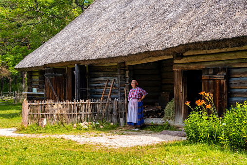 Tallinn, Estonia. June 10, 2021. Old woman standing at the entrance of her house in a countryside in Estonia. Rural concept