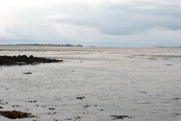 view to Lindisfarne island from causeway on dull day in summer in Northumberland