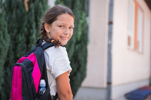 Happy young girl going to school without a protective mask