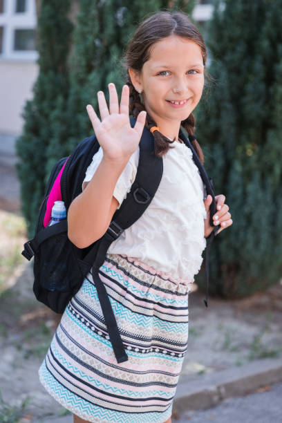 istock Happy school girl waving her hand 1331620030