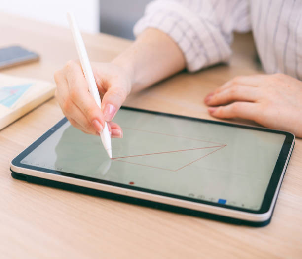 istock Young woman student draws geometric shapes in a digital tablet using a stylus. Math education online. Hand close up 1331623610