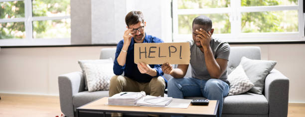 istock Couple Sitting On Couch Holding Help Sign 1331624515