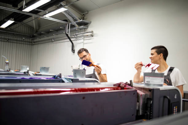 istock Printing machine operators working together with paint in print shop. 1331634207