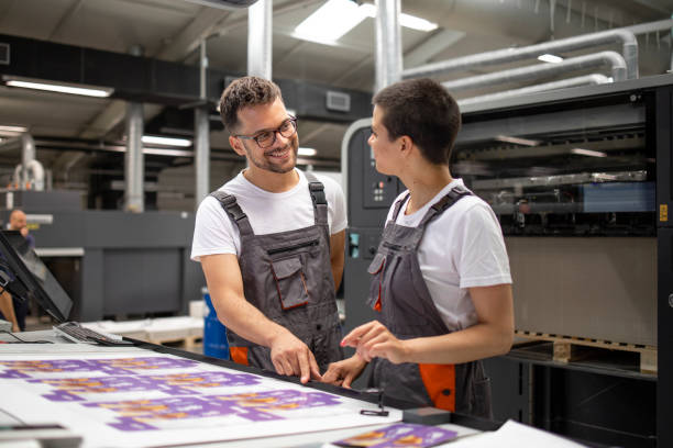 istock Printing machine operators checking graphic quality and color values at print shop. 1331634225