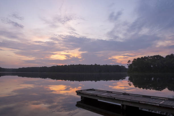 pre-dawn clouds over calm lake with rustic pier - color image light pink dramatic sky imagens e fotografias de stock