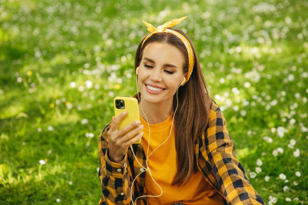 istock Beautiful woman sitting on the grass and using smart phone 1331640076