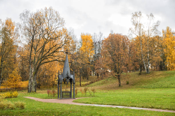 How picturesque autumn is. The leaves are shimmering in different colors, and this scent in the air evokes tranquility. In the photo, a cozy backyard with colorful trees, a manicured lawn with autumn flowers and an asphalt path that leads to an exquisite gazebo.