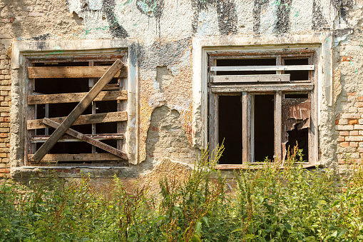 two windows of old abandoned house on city street on summer day