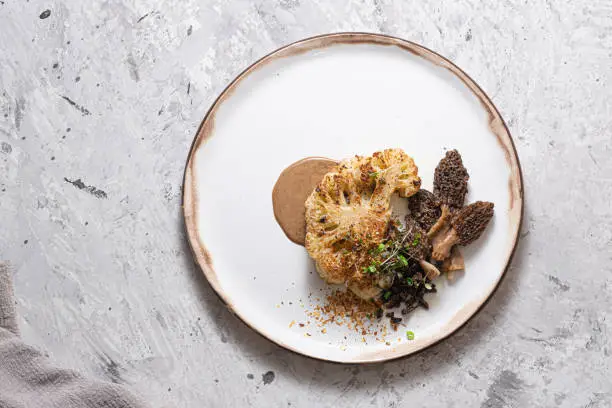 Cauliflower steak with morels on plate, restaurant dish, copy space.