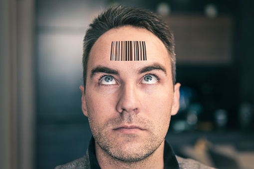 A man with a stupid expression looks at his qr code on his head. The concept of chipping the population. young man with a qr code on his forehead. global control and governance