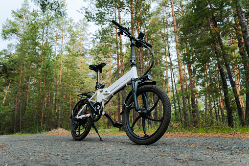 Eco friendly mode of transport. bicycle with an electric motor. An electric bike of white color on the background of a green forest.