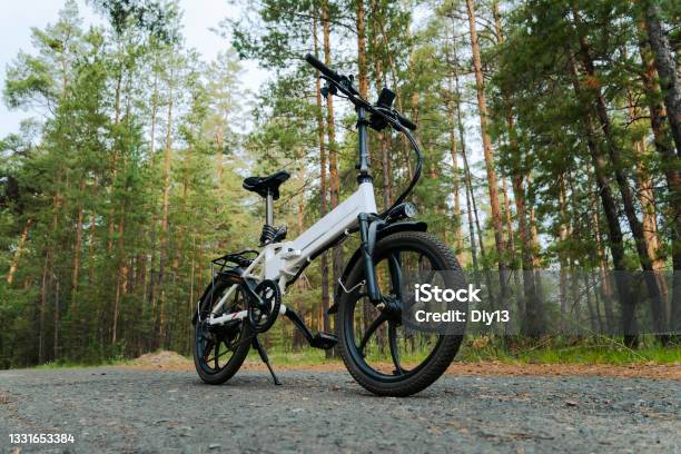 Eco Friendly Mode Of Transport A Bicycle With An Electric Motor An Electric Bike Of White Color On The Background Of A Green Forest Stock Photo - Download Image Now