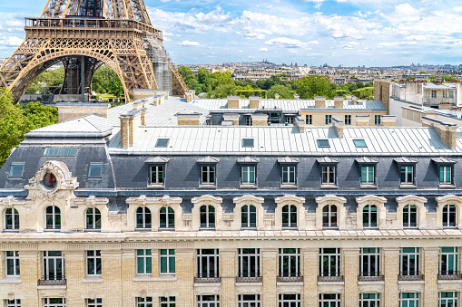 Paris, beautiful Haussmann facades in a luxury area of the capital, with the Eiffel Tower and Montmartre hill in background