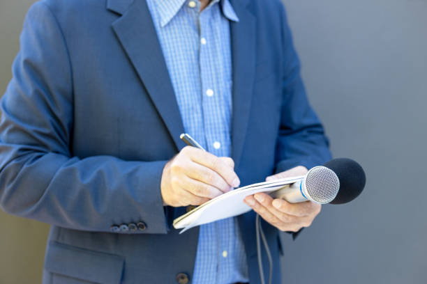 istock Journalist at news conference or media event, holding microphone, writing notes. Broadcast journalism concept. 1331661304