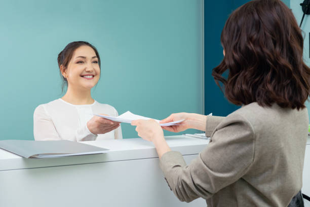receptionist accepts documents from the female visitor receptionist accepts documents from the female visitor. hotel reception stock pictures, royalty-free photos & images