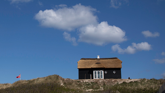 Summer house on a cliff with a danish flag behind.
